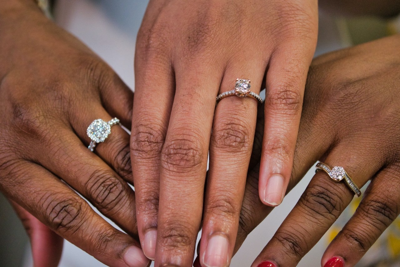 three hands wearing diamond engagement rings