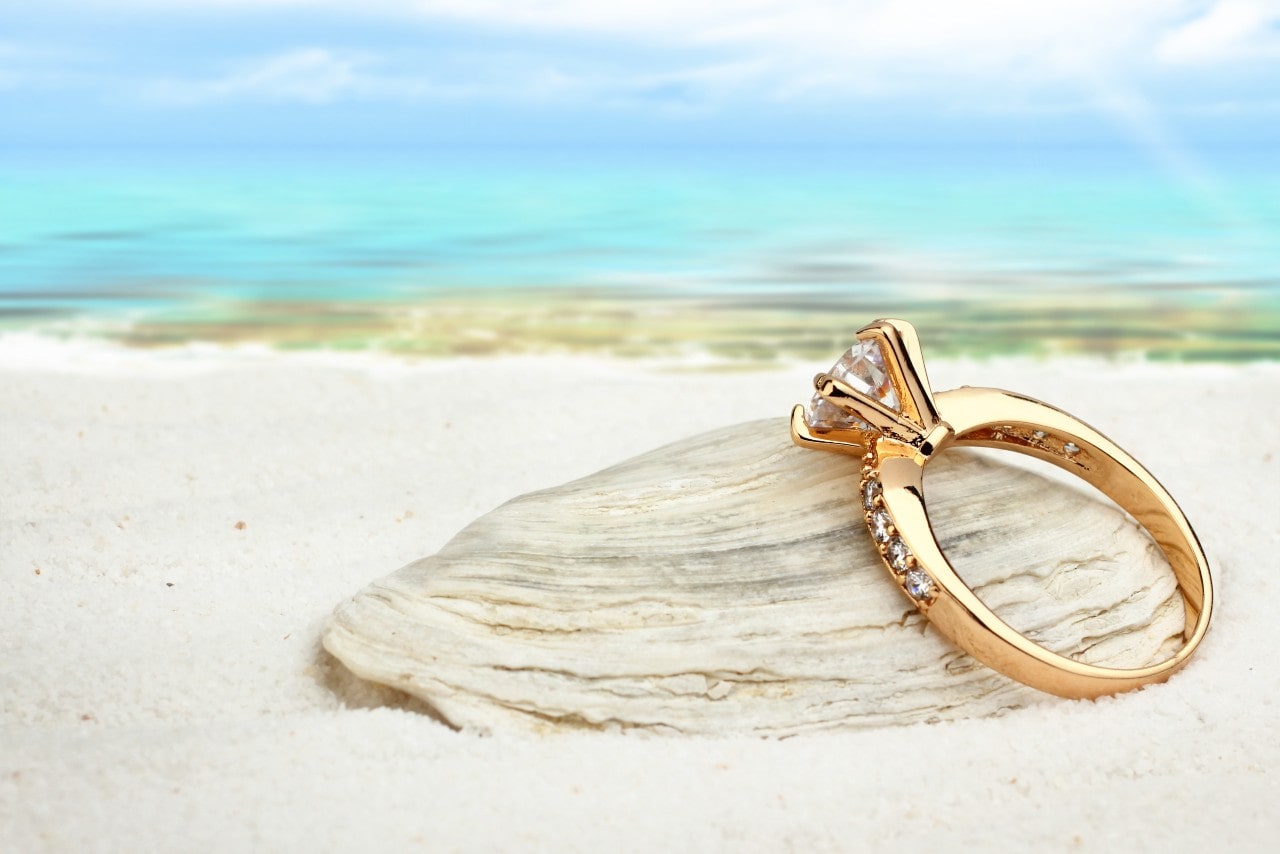 an engagement ring on a beach with classic prong setting