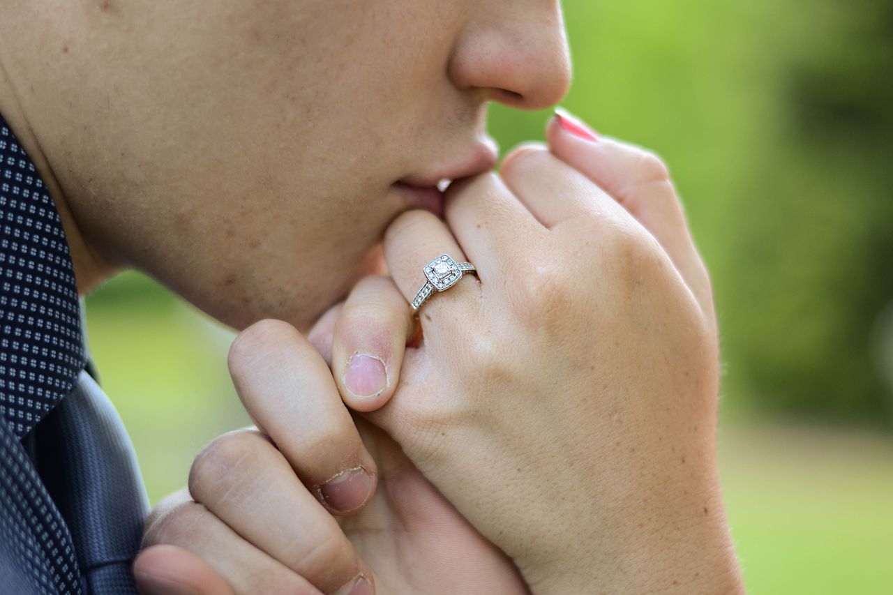 a man kissing a woman’s hand wearing an engagement ring