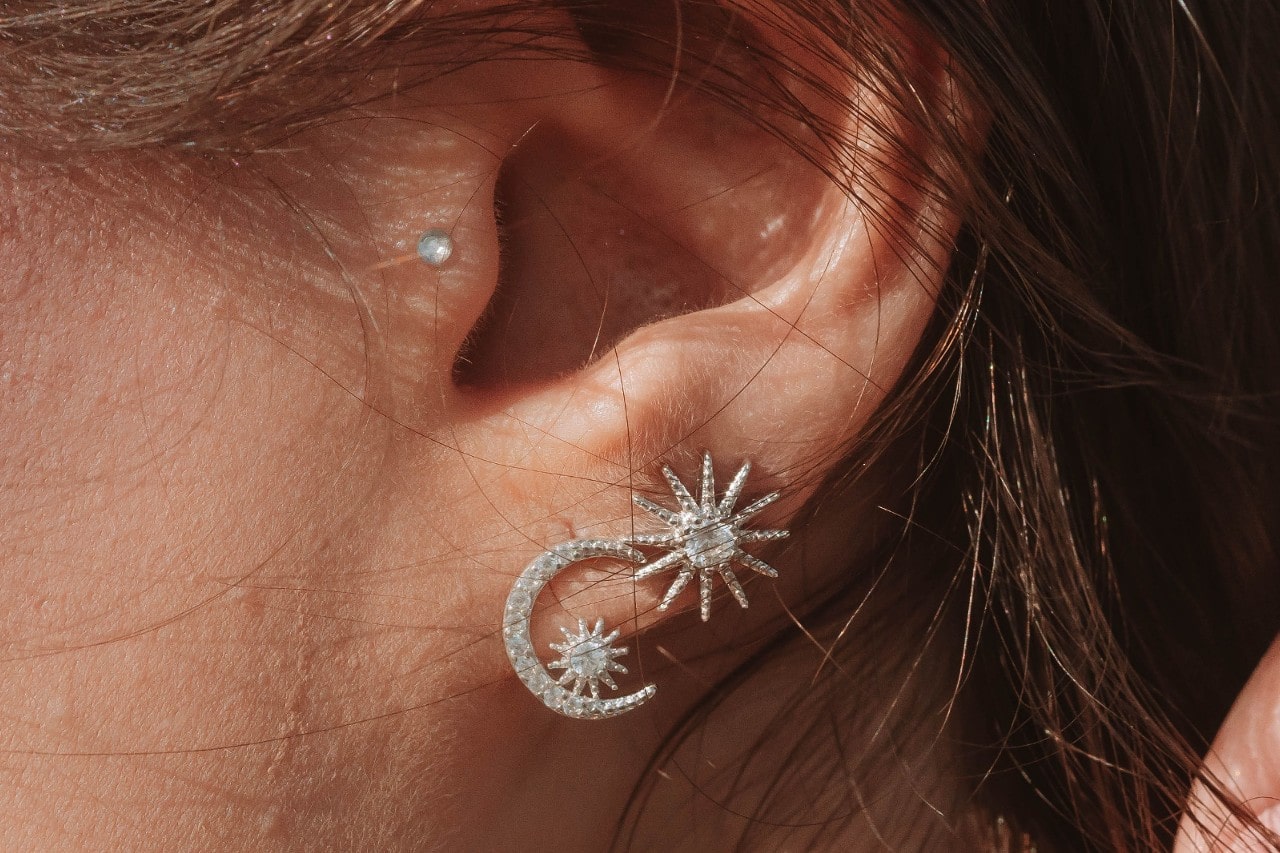close up image of a woman’s ear wearing three diamond earrings
