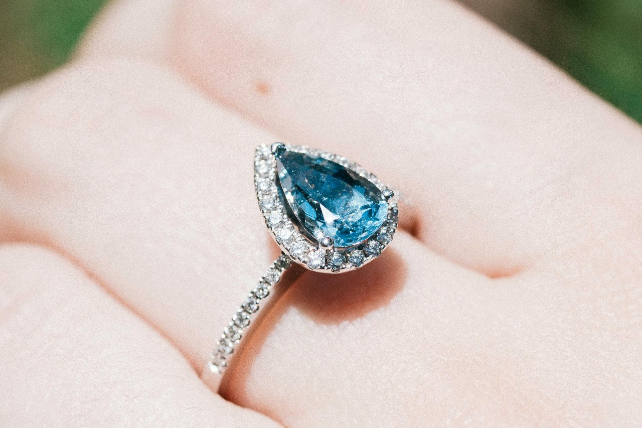 close up image of a person’s hand wearing a gemstone fashion ring