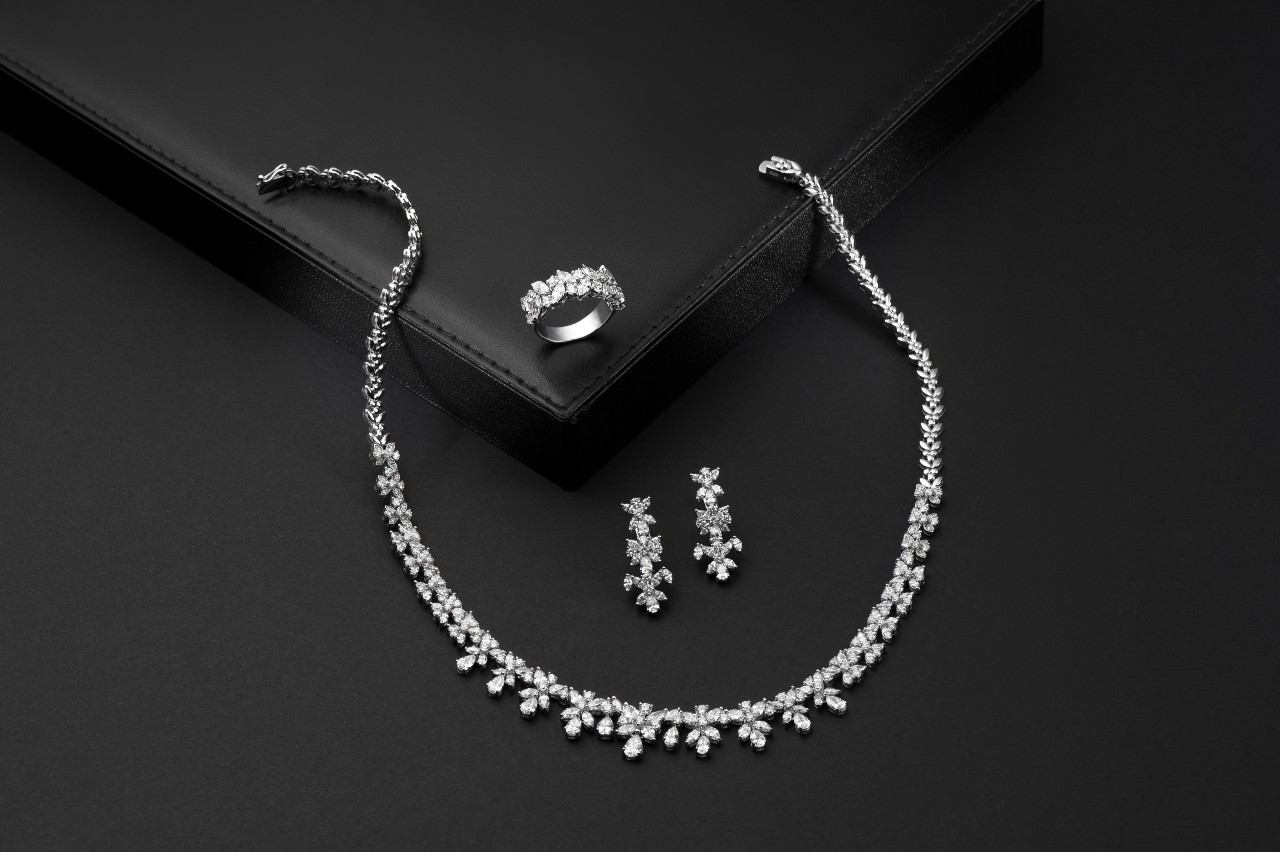 A close up of a diamond jewellery set: drop earrings, fashion ring and necklace.