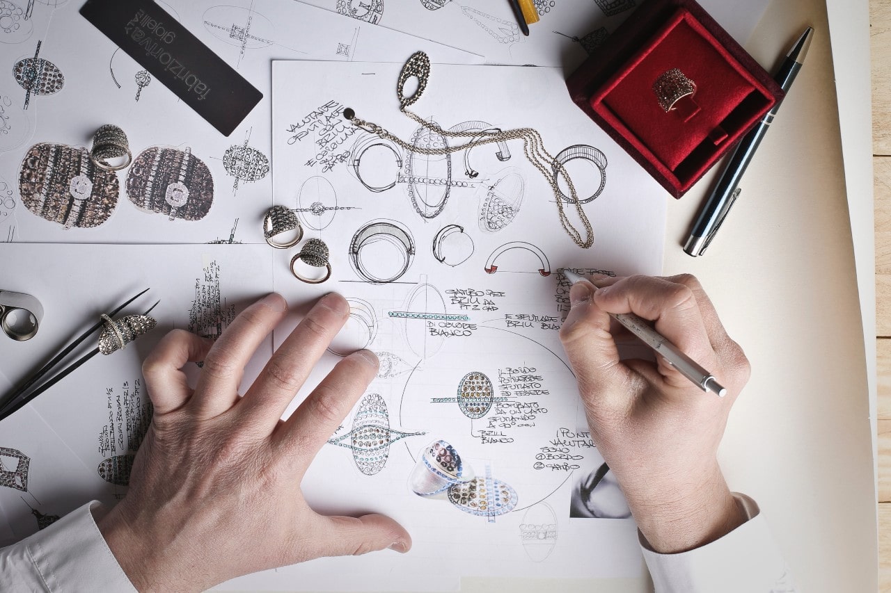 An overhead view of a jeweller sketching custom jewellery designs.