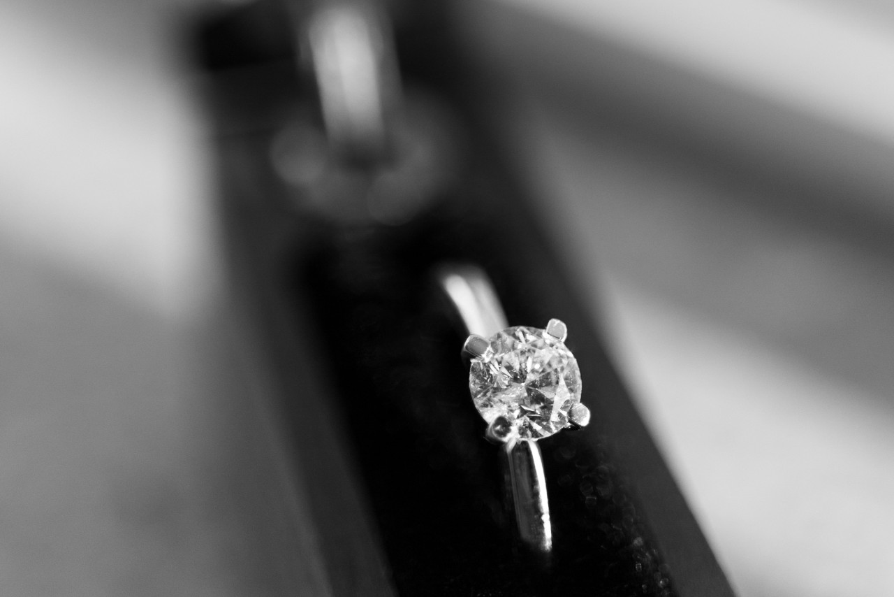 A white gold solitaire round-cut engagement ring on a black velvet holder against a blurry grey background A white gold solitaire round-cut engagement ring on a black velvet holder against a blurry grey background