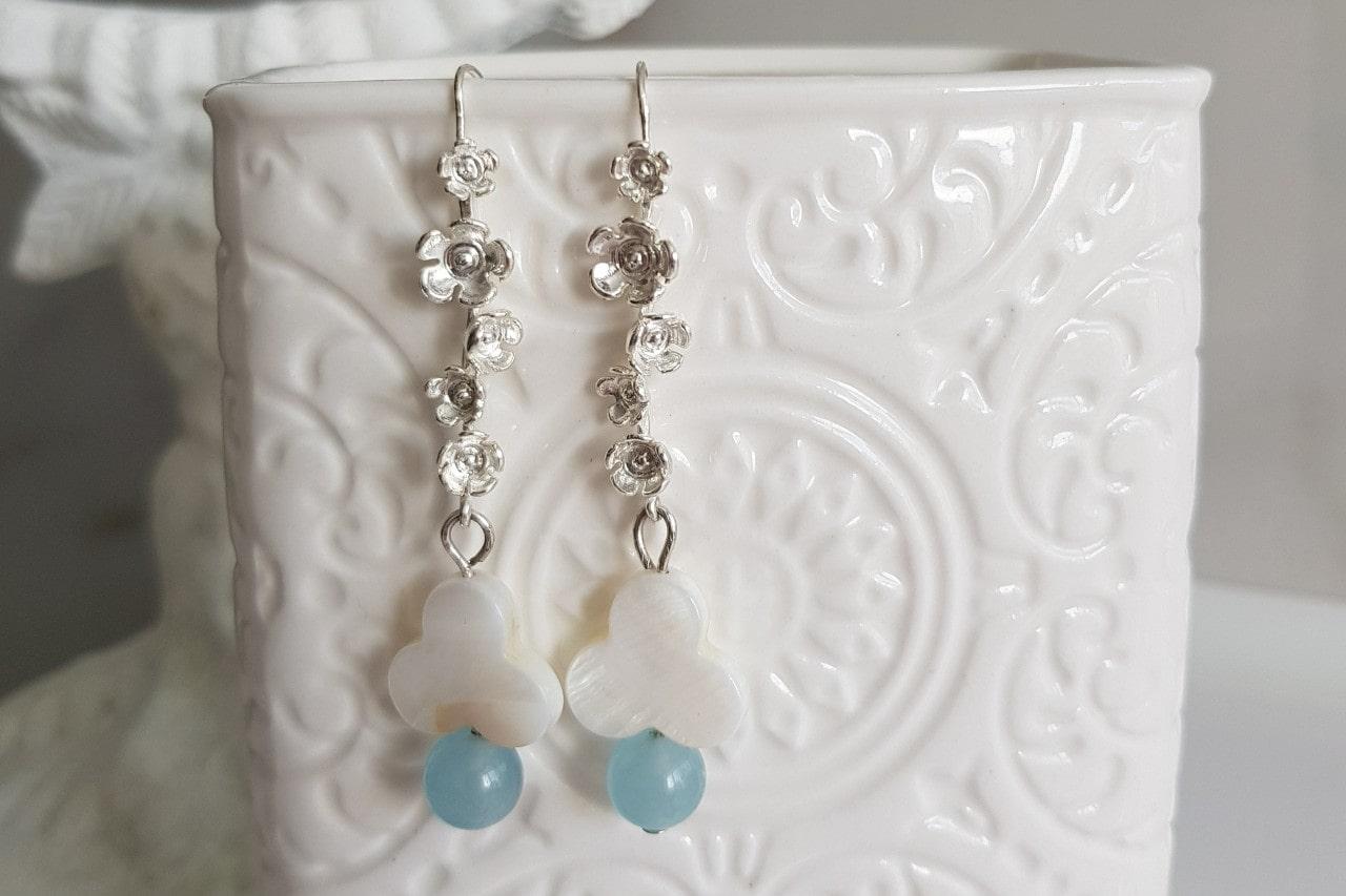 Drop earrings with gemstones and sterling silver on a porcelain vase