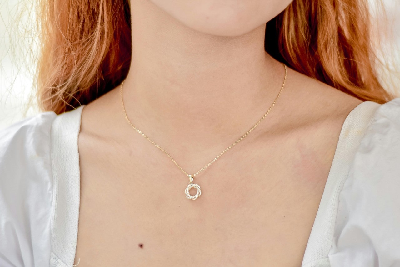 A close up of a woman’s neck adorned with yellow gold round necklace. A close up of a woman’s neck adorned with yellow gold round necklace.