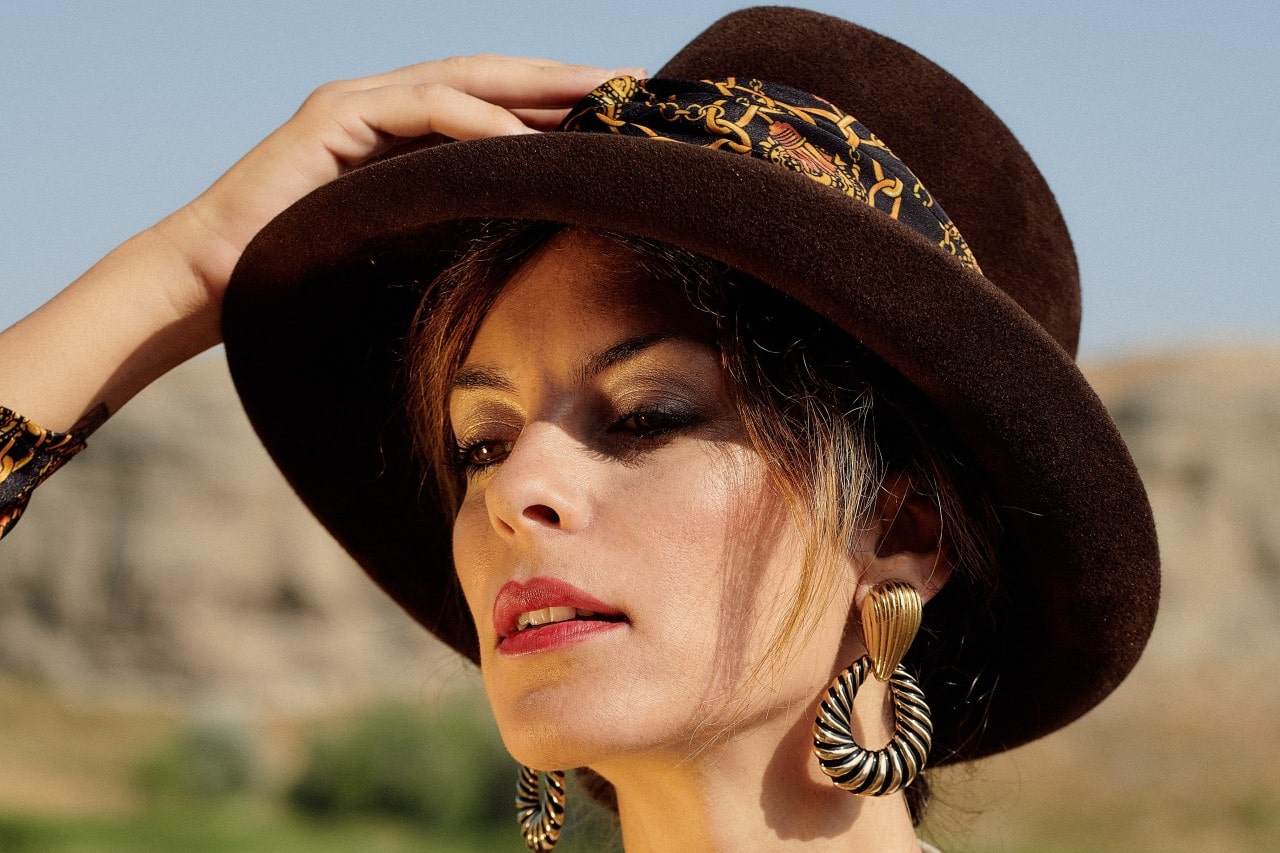 A close-up of a stylish woman wearing bold gold earrings and a fashionable hat. A close-up of a stylish woman wearing bold gold earrings and a fashionable hat.