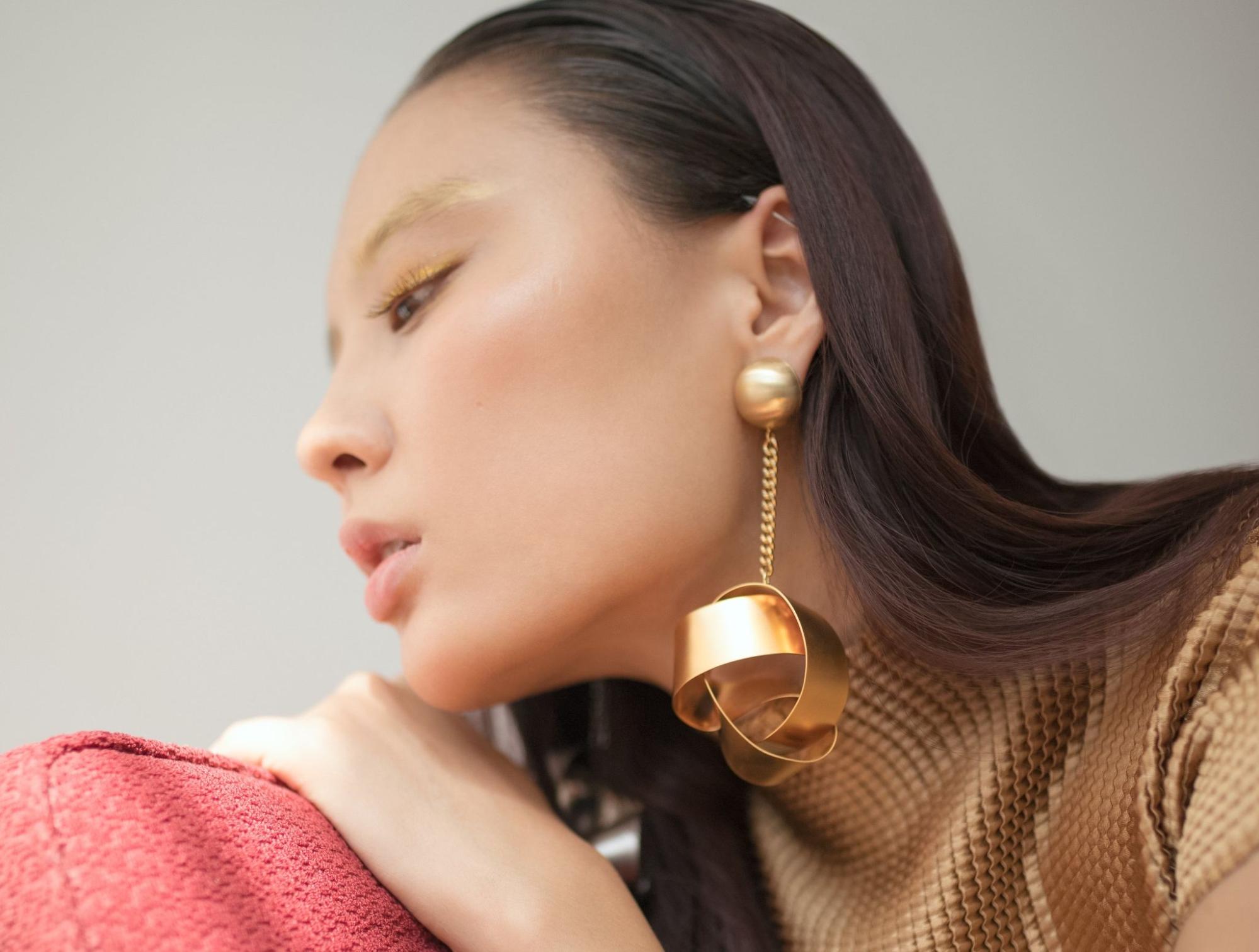 A close-up of an elegant young woman wearing a pair of distinctive gold earrings. A close-up of an elegant young woman wearing a pair of distinctive gold earrings.