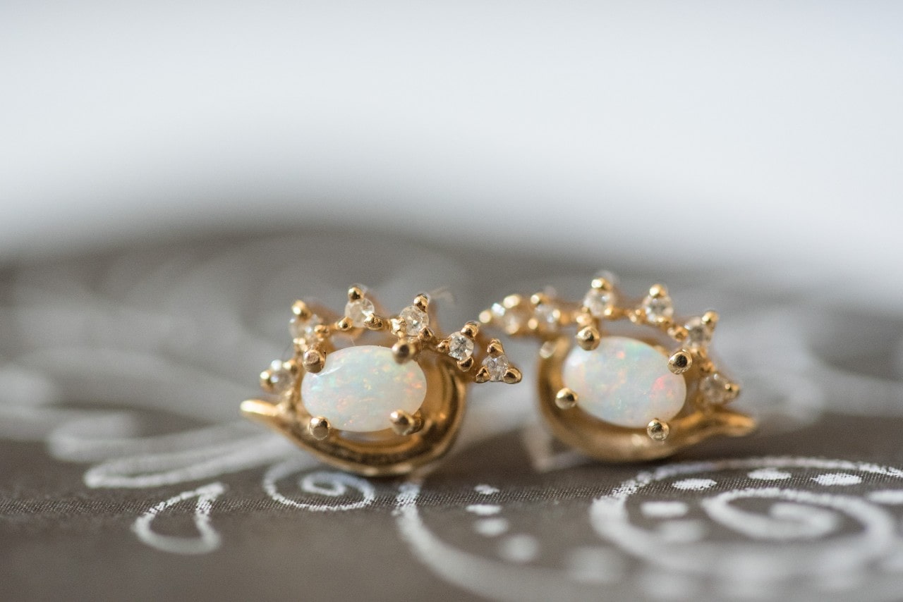 A close-up of elegant gold and mother of pearl stud earrings on a fabric backdrop. A close-up of elegant gold and mother of pearl stud earrings on a fabric backdrop.
