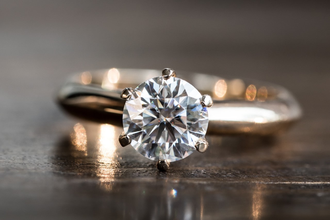 a round cut engagement ring resting on a table a round cut engagement ring resting on a table