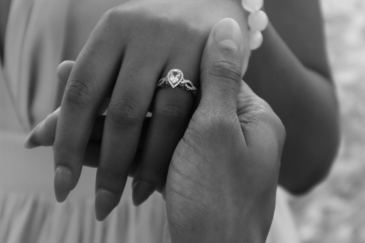 a man’s hand holding a lady’s hand that’s wearing a pear-shaped engagement ring a man’s hand holding a lady’s hand that’s wearing a pear-shaped engagement ring