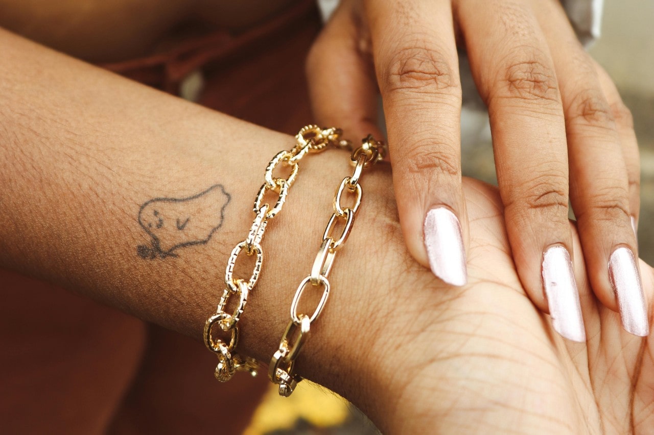 A close-up of a woman’s wrist adorned with a gold bracelet. A close-up of a woman’s wrist adorned with a gold bracelet.