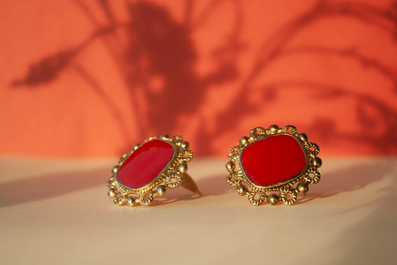 A close-up of ornate gold earrings on a vibrant background. A close-up of ornate gold earrings on a vibrant background.