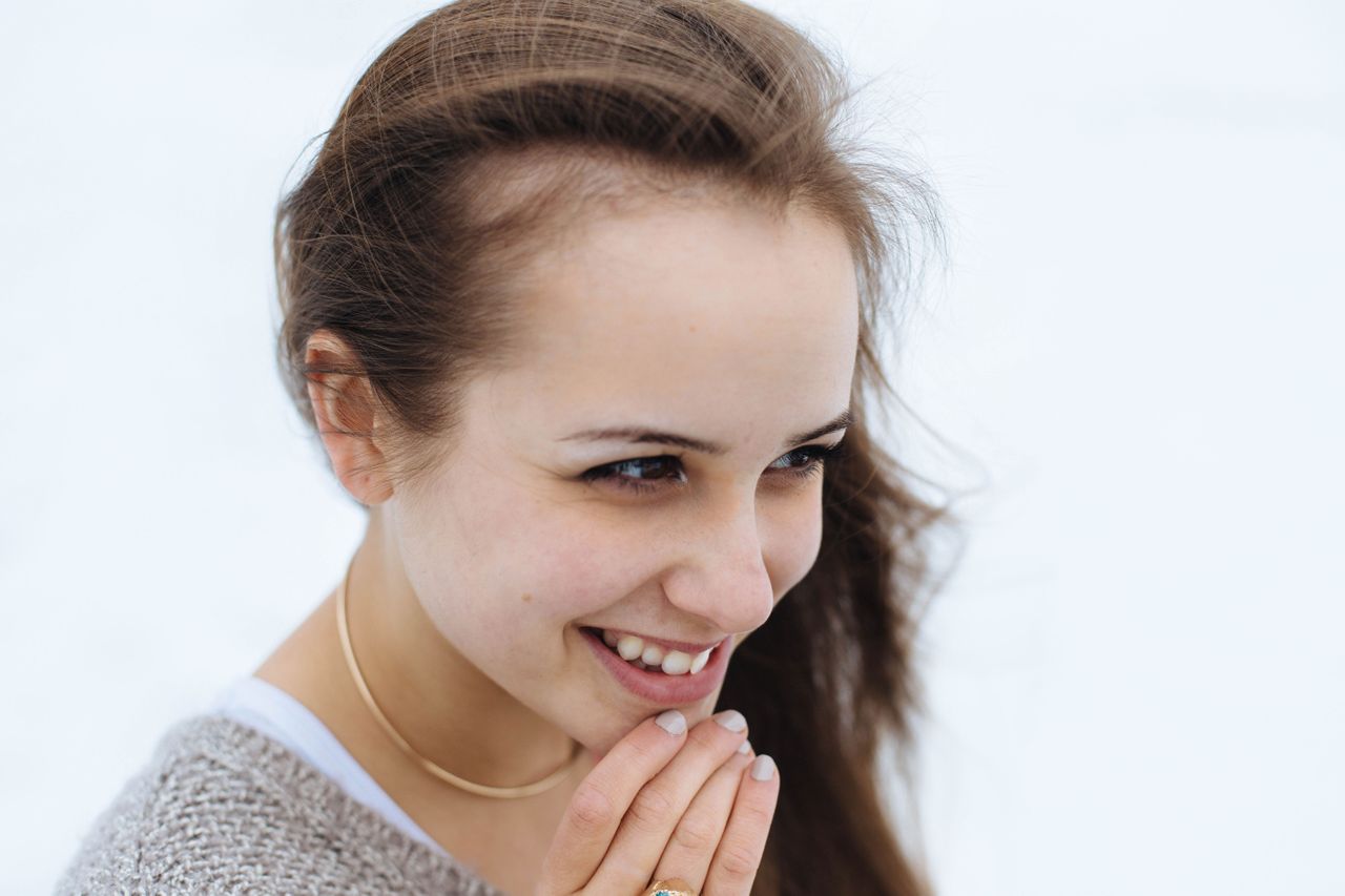 gold necklace on woman smiling looking to side gold necklace on woman smiling looking to side