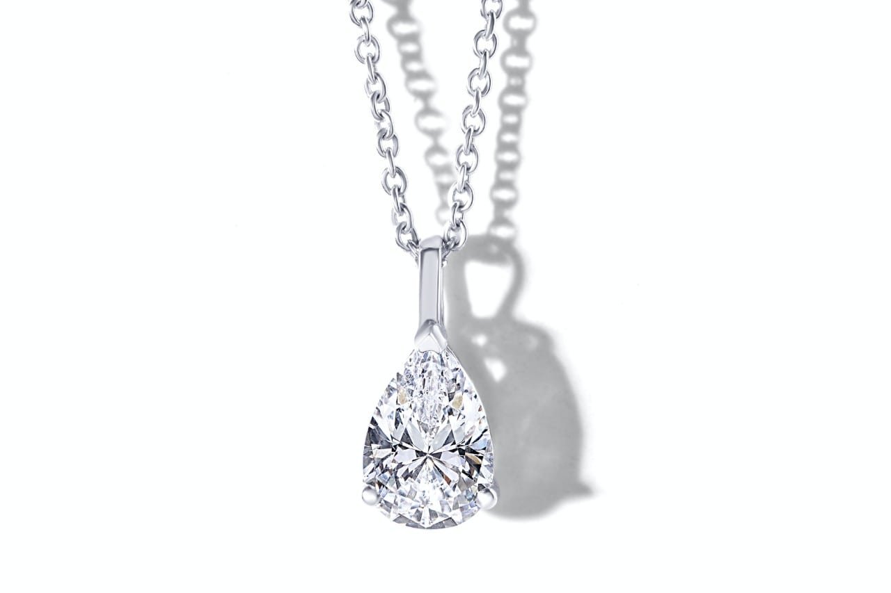 Close up image of a pear shape cut diamond necklace against a white background